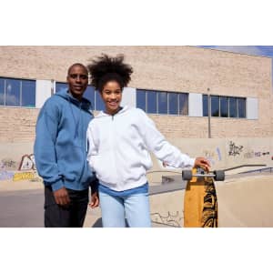 A blue oversized hooded jacket and a white oversized hooded jacket displayed on two individuals at a skate park.