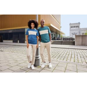 A colour-block T-shirt featuring blue, green, and white sections, worn by a man and woman standing outdoors.