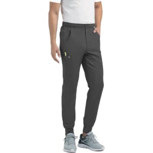 A pair of men's joggers in dark grey, featuring a half elastic waistband and side pockets. The model wears a plain white t-shirt.