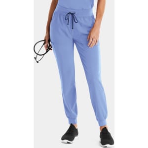 A pair of light blue women's joggers with a drawstring waist, featuring side pockets. The model holds a pair of glasses.