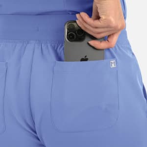 A pair of women's joggers in light blue, featuring a back pocket with a smartphone being inserted.