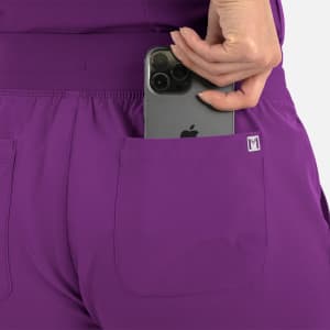 A pair of purple joggers with pockets, featuring a phone being placed in one of the back pockets.