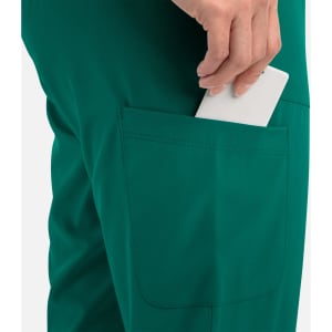A close-up of teal joggers with a hand inserting a phone into a side pocket. The joggers feature a logo.