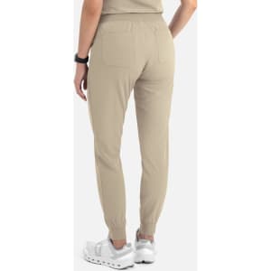 A women's jogger pant in beige, featuring a fitted ankle, pockets, and a comfortable waistband. Includes branding.