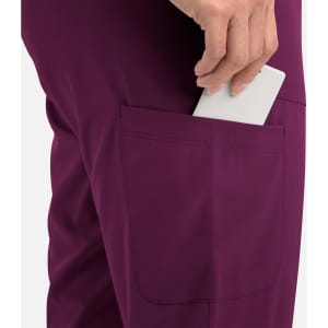 A close-up of a women's jogger in a deep purple colour, featuring a side pocket with a hand placing a card inside.