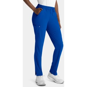 Blue women's skinny pull-on pants with pockets and an elastic waistband. The model stands wearing white shoes.