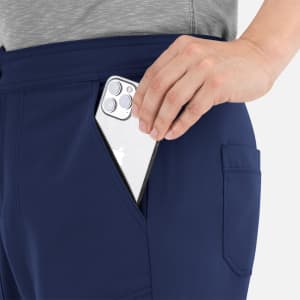A hand inserting a smartphone into the pocket of navy cargo pants featuring a half elastic waistband.