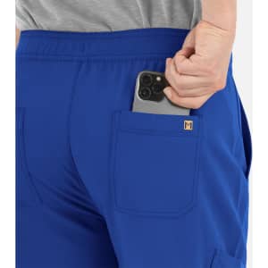 A pair of blue cargo pants with a half elastic waistband and a phone partially tucked in the back pocket.