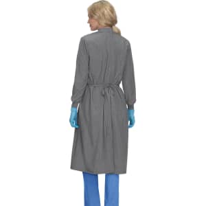 A clinical cover gown in grey, featuring a back tie and long sleeves, worn by a person with blue gloves.
