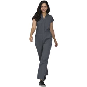 A jumpsuit in dark grey, featuring short sleeves and a relaxed fit, modelled by a woman walking.