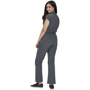 A grey jumpsuit with short sleeves and a cinched waist, worn by a woman. It features pockets and black shoes.
