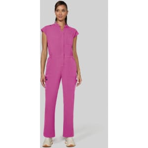 A pink jumpsuit with short sleeves and a front pocket, modelled by a woman against a grey background.