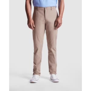 Beverly Chino Trousers in light beige, featuring a slim fit and front pockets. The model is wearing white sneakers.