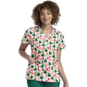 A woman wearing a short-sleeve, pink V-neck top with a festive print of Christmas trees, snowmen, and decorations.