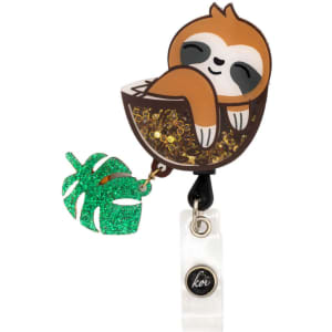 A sloth-shaped shaker badge with glitter and a green leaf charm, featuring a logo on the bottom.