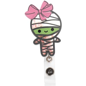A Koi Shaker Badge features a cute mummy character with a pink bow, sparkling accents, and a small logo.