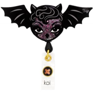 A black bat-shaped badge featuring a sparkly purple and black face with decorative wings and a tag.