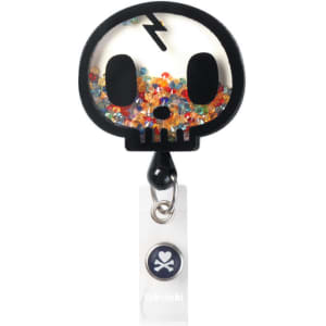 A black shaker badge featuring a skull design filled with colourful glitter and a small branding logo.
