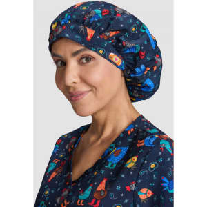 A navy bouffant scrub cap featuring colourful patterns of animals and celestial designs, worn by a smiling woman.