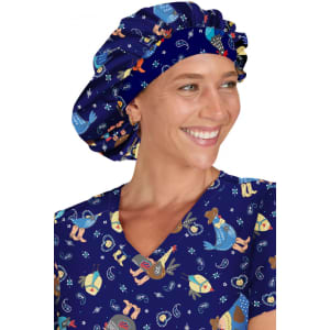 A bouffant scrub cap in navy blue featuring colourful designs, worn by a smiling individual in matching scrubs.