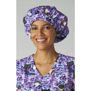 A bouffant cap featuring a purple floral print, worn by a smiling woman in a matching scrub top.