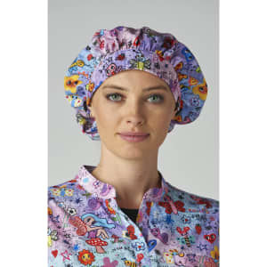A bouffant cap in pink, featuring a colourful print of flowers and butterflies, worn by a woman.