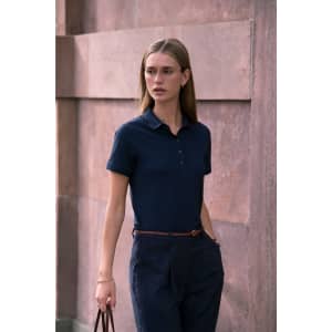 A navy women's polo shirt with a classic collar and buttons, paired with tailored dark trousers.