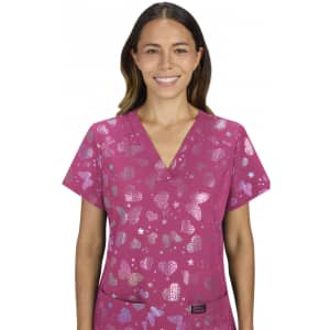 A woman wears a vibrant pink scrub top featuring a butterfly pattern and stars, with a logo on the chest.
