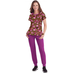 A woman is wearing a brown and pink patterned top with purple pants and black sneakers, featuring a logo.
