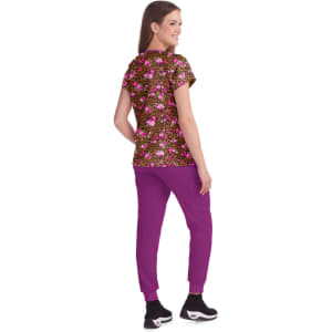 A woman is wearing a floral print top with pink, purple, and yellow hues, paired with purple joggers.