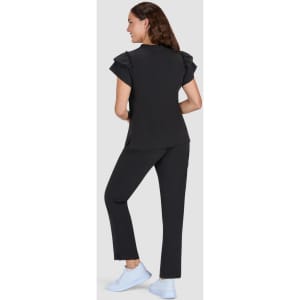 A black top with ruffle sleeves paired with black pants, modelled from the back, featuring light blue footwear.