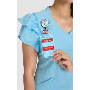 A blue top with ruffled sleeves, featuring a badge holder with a decorative clip and a bird design.