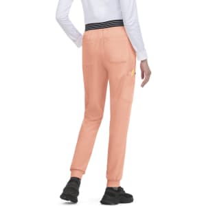 A pair of peach joggers with a black waistband and pockets, worn by a person facing away.