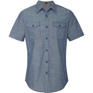 A short sleeve chambray shirt in light blue with two chest pockets and button-up closure, featuring a brand logo.