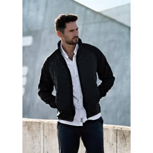 A soft shell jacket in black, featuring a zip front and a modern design, displayed on a man outdoors.