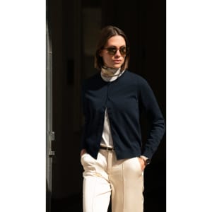 A navy cardigan for women, featuring a button-up front and worn with a white top and light trousers.