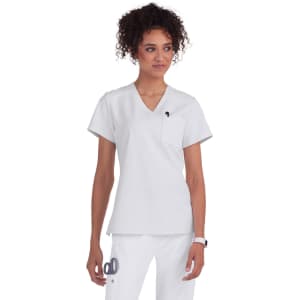 A medical scrub top in white, featuring a V-neck design and a pocket, worn by a woman with curly hair.