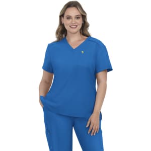 A woman wearing a blue medical scrub top with a pocket, featuring a logo on the chest. She has wavy hair and is smiling.
