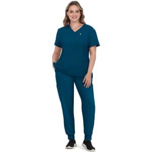 A model wearing a teal scrub set consisting of a V-neck top and tapered pants, with a logo on the top.