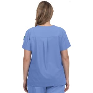A blue medical scrub top featuring a pleat detail at the back, worn by a female model. It has a logo on the sleeve.