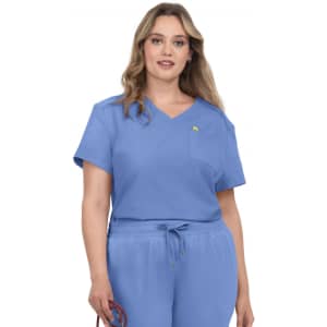 A woman wearing a light blue scrub top with a pocket and short sleeves, featuring a small logo.