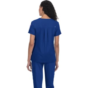 A blue medical scrub top with a relaxed fit, featuring a pleat detail at the back and a logo on one sleeve.