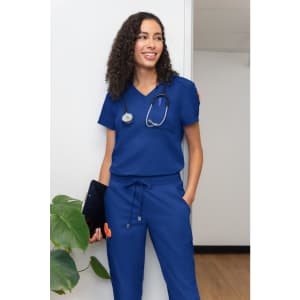 A woman wearing a blue medical scrub set with a stethoscope around her neck, standing in an indoor setting.