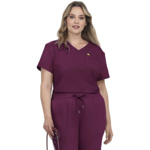 A woman wearing a short-sleeved, burgundy medical scrub top with a pocket and matching jogger-style pants.
