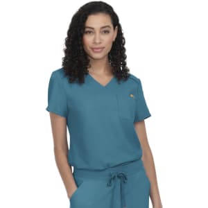 A teal scrub top featuring short sleeves and a pocket, worn by a model with curly hair.