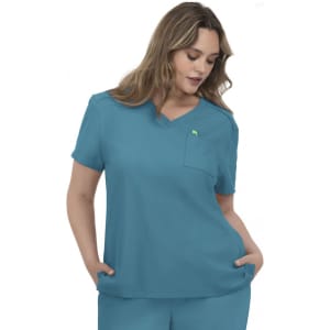 A woman wearing a teal scrubs top with a v-neck and a chest pocket. The top has a logo on it.