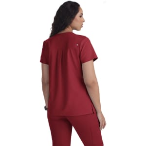 A red scrubs top featuring a back pleat design, short sleeves, and a logo.