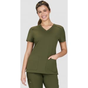 A scrub top in olive green with a V-neck design and two front pockets, modelled by a smiling woman.
