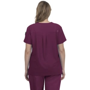 A back view of a woman wearing a burgundy scrub top. The top features a pleat detail and a logo on the sleeve.