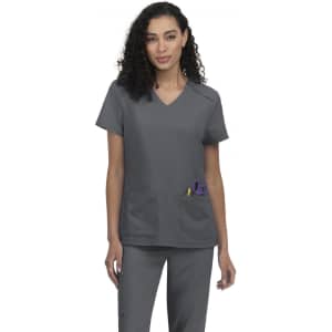 A grey scrub top featuring a V-neck design and two front pockets. The model has curly hair and stands confidently.